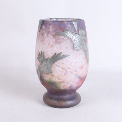 un vase violet orné d'un oiseau, posé sur un fond blanc