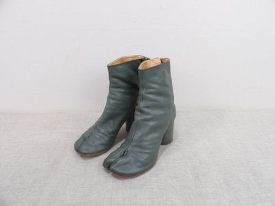 une paire de bottines en cuir vert posées sur une surface blanche