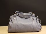 le sac à main gris est posé sur une table devant un fond noir