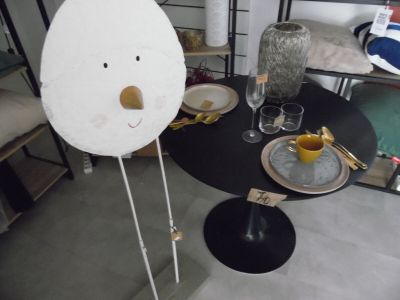 une table sur laquelle sont posés des assiettes et des verres, avec un visage en papier