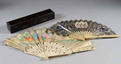 Plusieurs éventails chinois anciens sont posés sur une table, à côté d'une boîte