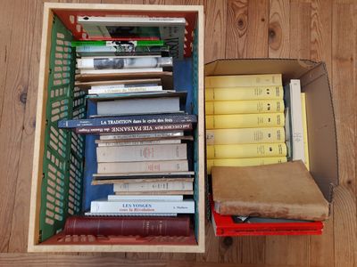 une boîte remplie de livres posée sur un plancher en bois