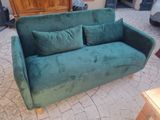 a green couch with two pillows on it in a living room