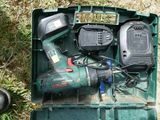 une boîte verte contenant des outils, posée sur l'herbe