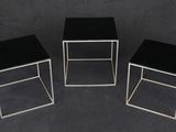 three black and silver side tables on a black background
