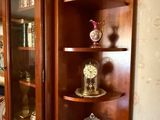 une armoire d'angle avec une porte vitrée et une horloge posée dessus
