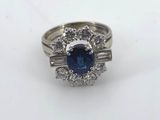 a close up of a blue sapphire and diamond ring on a white surface