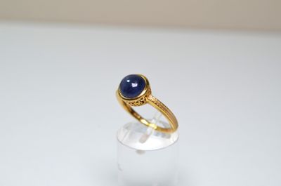 Gros plan sur une bague en or ornée d'une pierre bleue