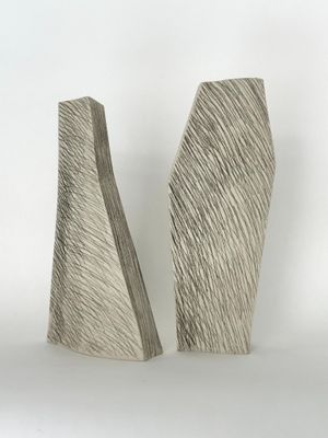 une paire de sculptures abstraites posées sur une surface blanche, avec un fond blanc
