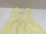 a yellow dress sitting on a white table with a white background