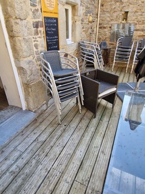 des tables et des chaises sur une terrasse en bois à l'extérieur d'un bâtiment