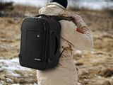 un homme avec un sac à dos, debout dans la neige