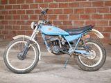a blue dirt bike parked in front of a brick wall