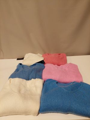 several sweaters are stacked on top of each other on a table