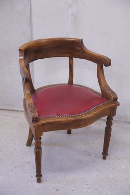 une chaise en bois avec une assise en cuir rouge posée sur un sol en béton