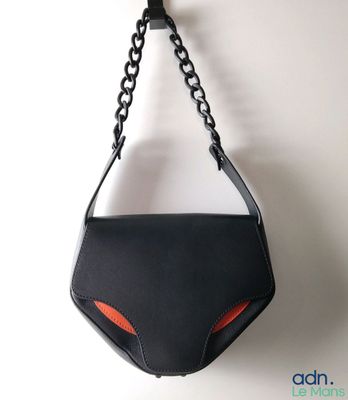 Le sac à main noir et orange est accroché au mur.