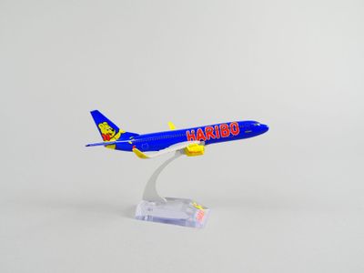 un petit avion miniature posé sur un socle transparent, sur fond blanc