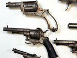 five old revolvers on a white surface with a white background