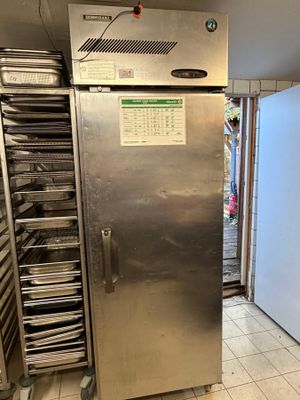 a large stainless steel refrigerator in a kitchen with lots of trays of food
