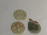 three pieces of carved jade are sitting on a white surface