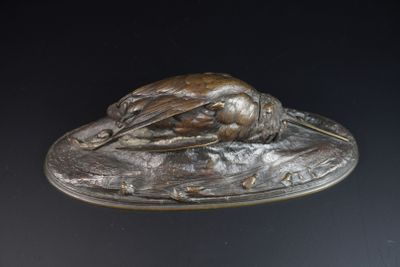 une statue en bronze représentant un oiseau posée sur un plateau