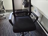 a black office chair sitting in front of a computer desk