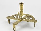 un microscope ancien plaqué laiton posé sur un support, sur fond blanc
