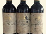 trois bouteilles de vin rouge posées l'une à côté de l'autre sur une surface blanche