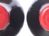 two bottles of wine with red caps on each of them