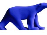 a blue plastic bear that is standing on a white surface