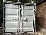 two white shipping containers sitting next to each other in the yard