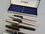 trois stylos et un stylo dans une boîte posée sur une table