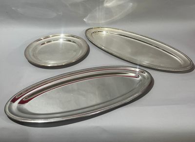 trois plateaux en argent et une assiette en argent posés sur une table blanche