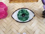a green and white eye sitting on the floor next to a pair of shoes