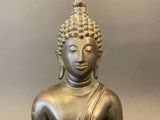 statue of a seated buddha holding a bird in his right hand