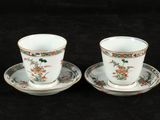 pair of cups and saucers with floral designs on them on a black background