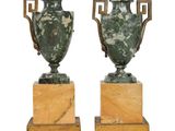 une paire de vases en marbre vert reposant sur des socles en bois, sur fond blanc