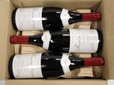 four bottles of wine in a cardboard box on a table