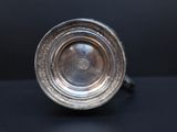 an antique silver plate on a black surface with a black background
