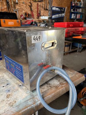 une boîte métallique à laquelle est raccordé un tuyau, posée sur une table