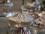 une table en verre sur laquelle sont posés des vases en argent, posée à son tour sur une table en verre