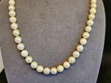un collier de perles blanches sur un mannequin avec un fermoir en or