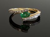 an emerald and diamond ring on a black surface