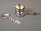 une tasse en argent avec une cuillère et un repose-cuillère posés sur une table