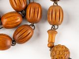 a close up of a wooden bead necklace on a white surface