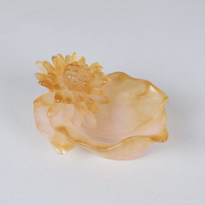 a yellow flower in a shell on a white surface