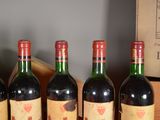 four bottles of red wine are lined up on a table