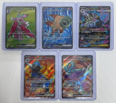 four different pokemon cards in plastic cases sitting on a table
