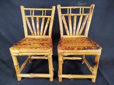 une paire de chaises en bambou avec des assises rembourrées, sur fond noir