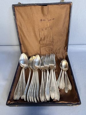 des couverts dans un coffret posé sur une table, sur fond blanc